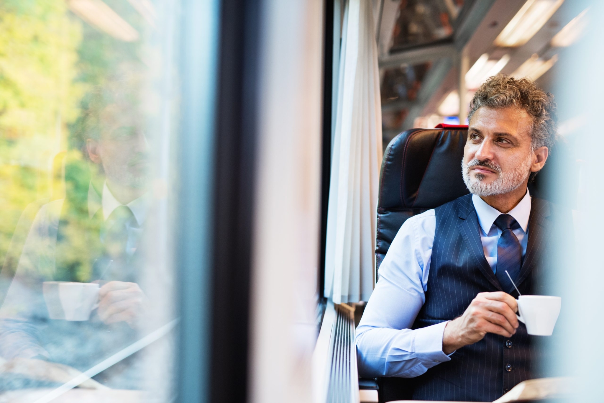 Mature businessman with coffee travelling by train